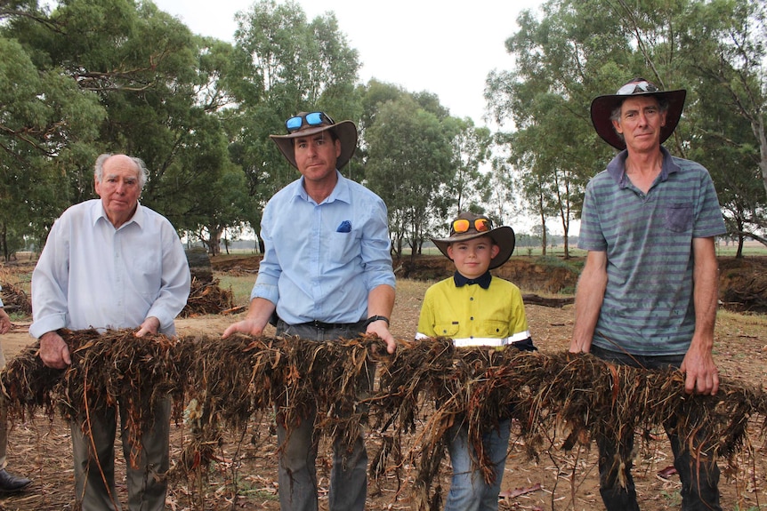 Three generations of Bennetts hold up fencing destroyed by the December flood.