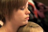 A teenage mother with her daughter in a classroom