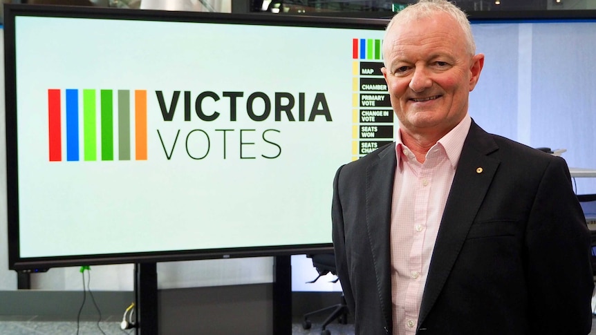 Antony Green stands in front of a Victoria Votes graphic on a large TV screen.