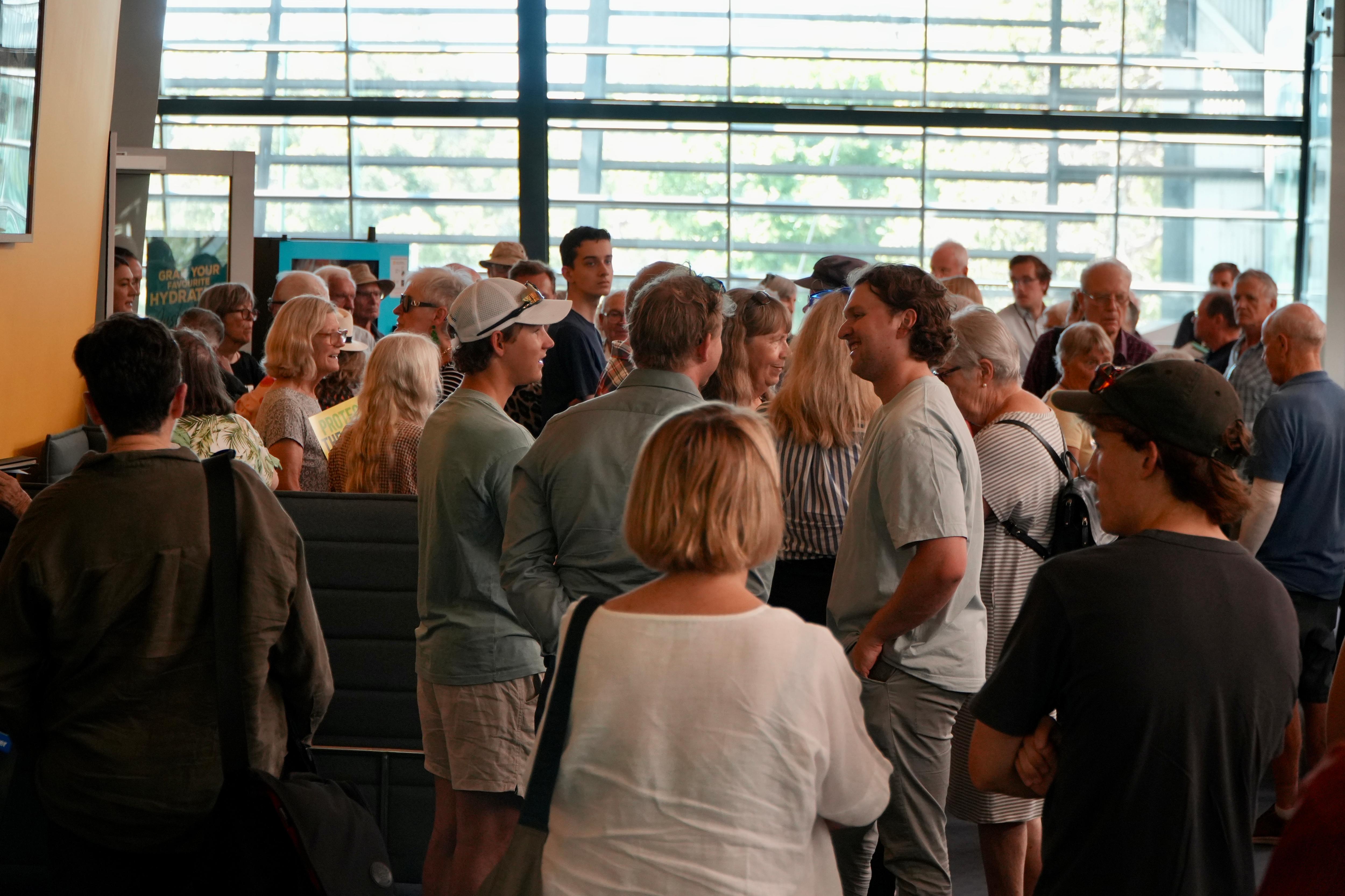 Decenas de personas en una galería acristalada abarrotada.