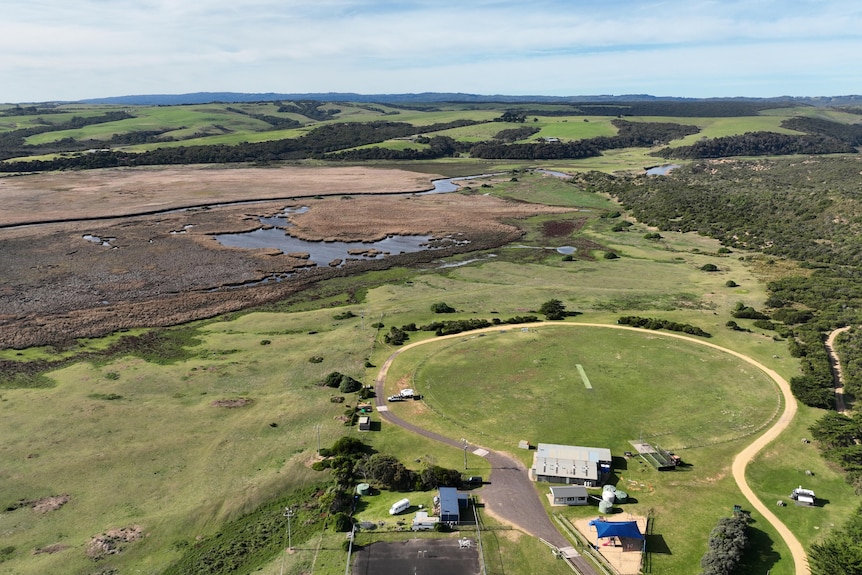 A bird's eye view of a recreation reserve surrounded by green grassland and swamp by a river.