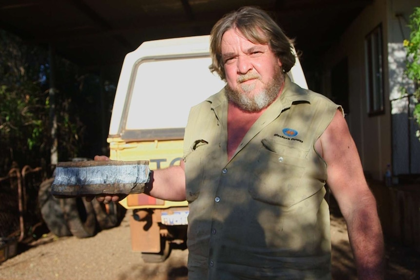 Mario Hartman holds up a rock with naturally occurring blue asbestos.