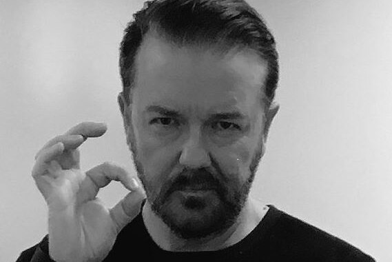 Close-up of Ricky Gervais giving OK signal with his forefinger and thumb forming a loop.