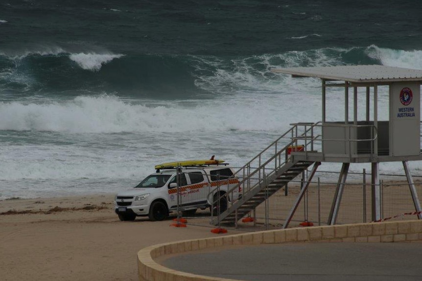 A Surf Life Saving WA vehicle parked on the sand at City Beach as waves break in the background.