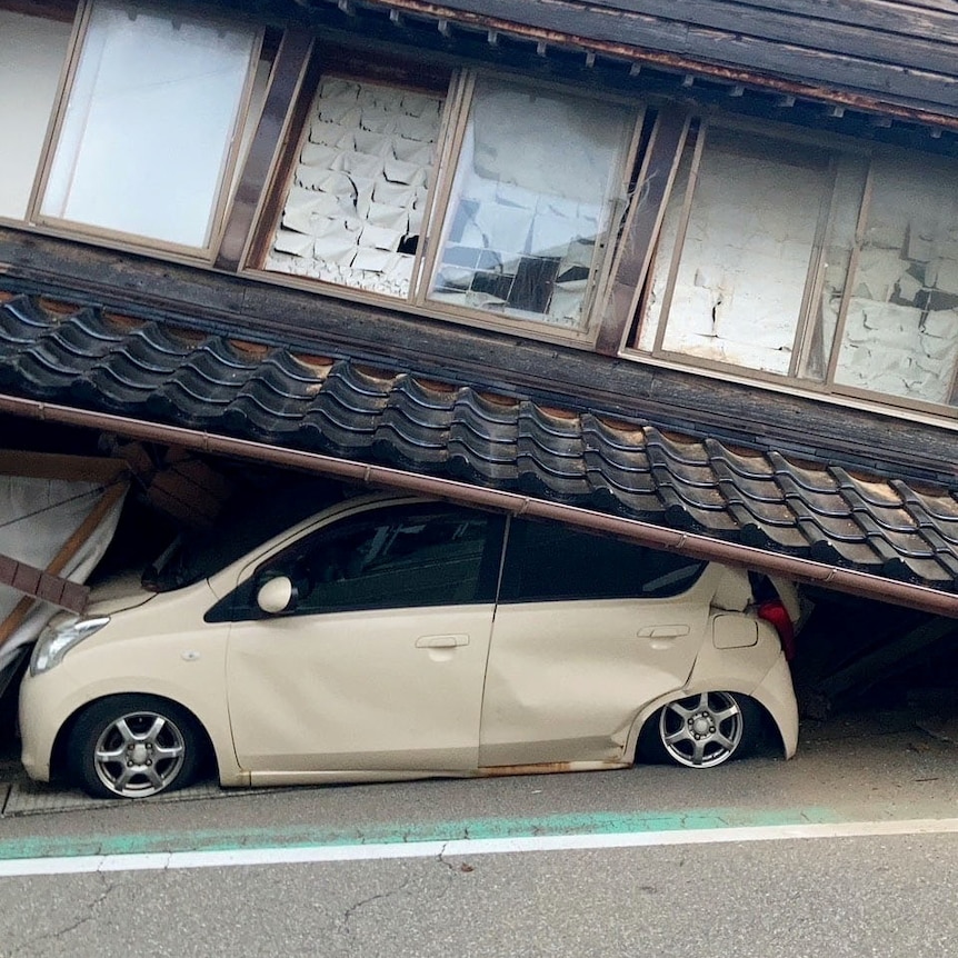 A car is trapped under a collapsed house following an earthquake in Japan.