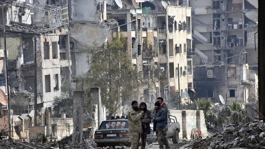Syrian troops and pro-government stand in the Ansari neighbourhood in East Aleppo