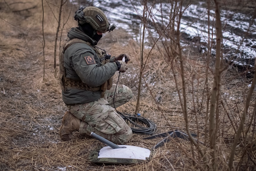 一名乌克兰士兵在前线阵地上准备星链卫星互联网系统。