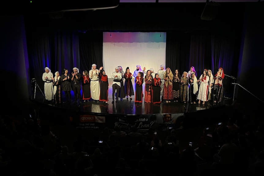 A group of performers on a stage in traditional Palestinian clothing.