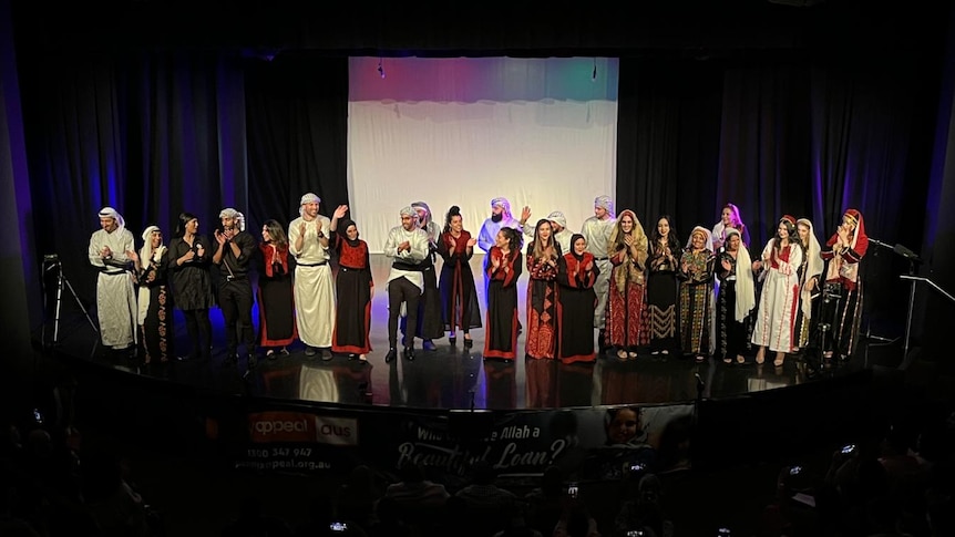 A group of performers on a stage in traditional Palestinian clothing.