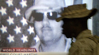 A US Marine walks past a television showing a portrait of US soldier Specialist Jeremy Sivits.