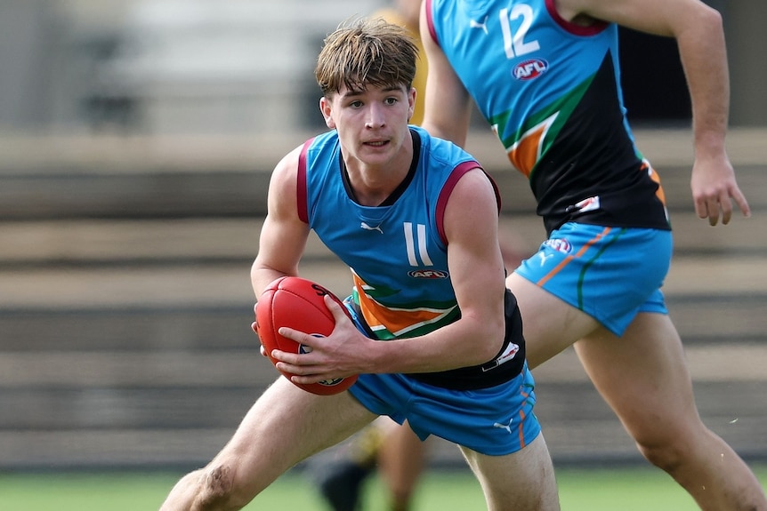 Phoenix Gothard holds the ball while playing Australian rules football.