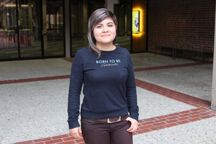 A woman stands in an outdoor courtyard.