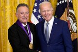 Bruce Springsteen, with a medal around his neck, stands next to Joe Biden