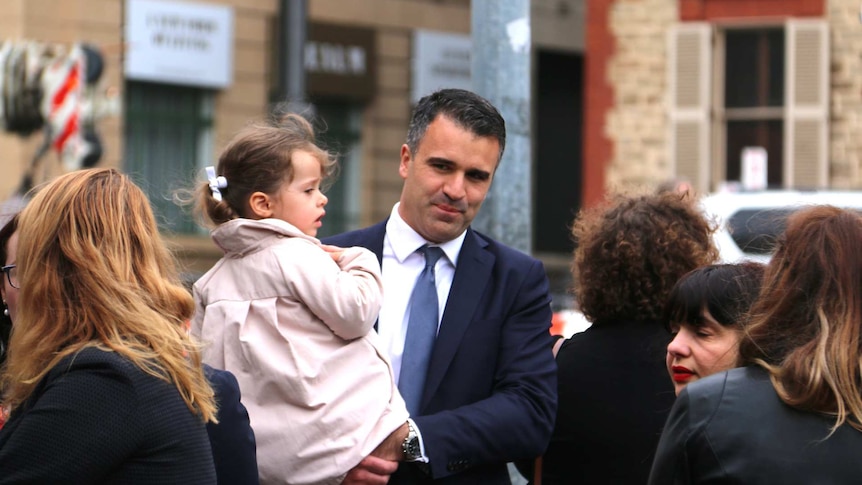 A man holds a child in public.