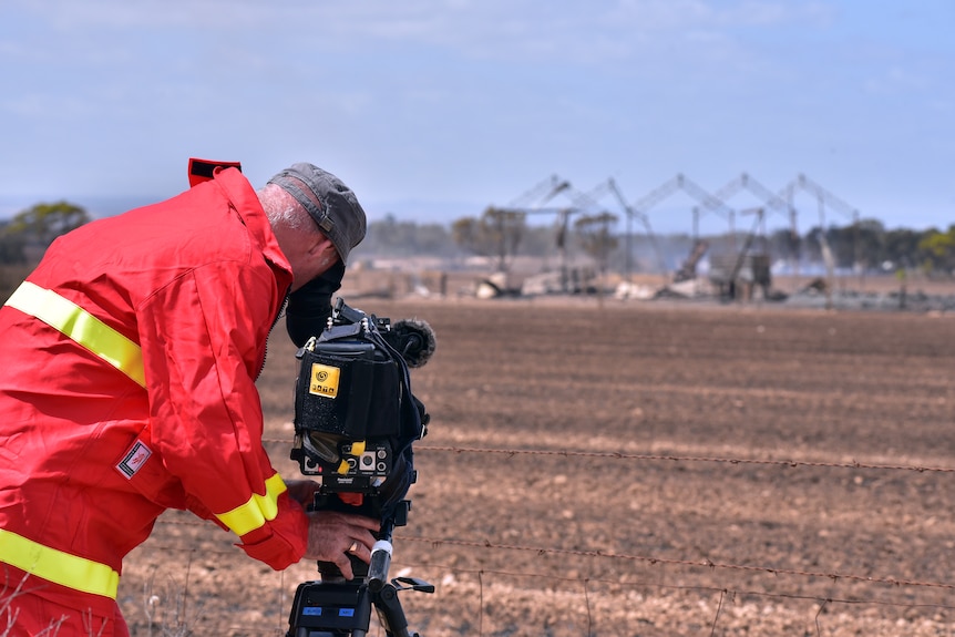 ABC cameraman Andrew Burch films a shed fire at Wasleys, days after the Pinery bushfire emergency in November 2016.