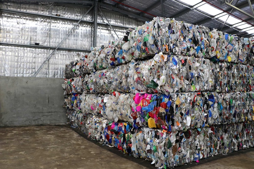 A big cube of recycled materials all compressed together in the corner of a warehouse.