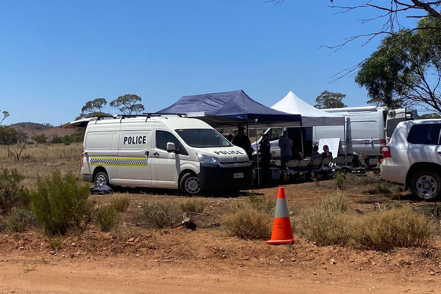 A police van and marquees next to a country road