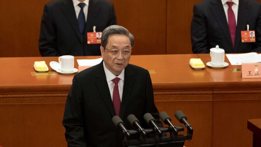 Wide high-angle shot of a man standing at a microphone and speaking.