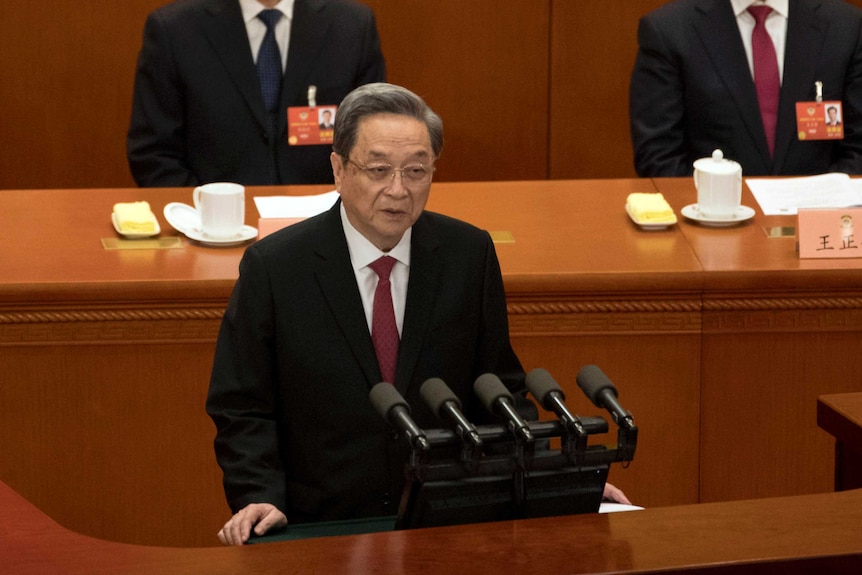 Wide high-angle shot of a man standing at a microphone and speaking.