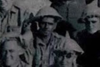 A grainy black and white photo shows a group of soldiers in fatigues and helmets posing for a photo
