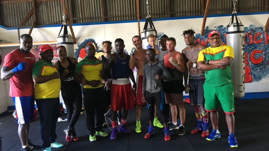 Cameroon boxers and local boxers from Warwick stand in front of punching bags