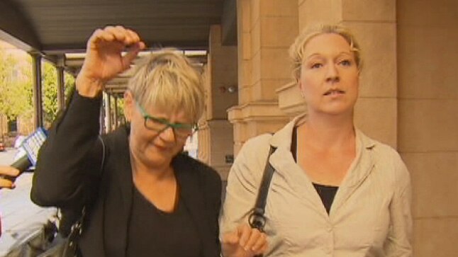 Two women walk along outside an Adelaide court.