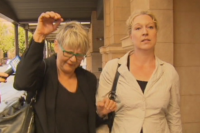 Two women walk along outside an Adelaide court.