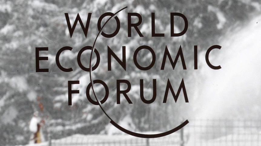 A worker removes snow in front of a logo from the World Economic Forum in Davos, Switzerland.