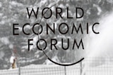 A worker removes snow in front of a logo from the World Economic Forum in Davos, Switzerland.