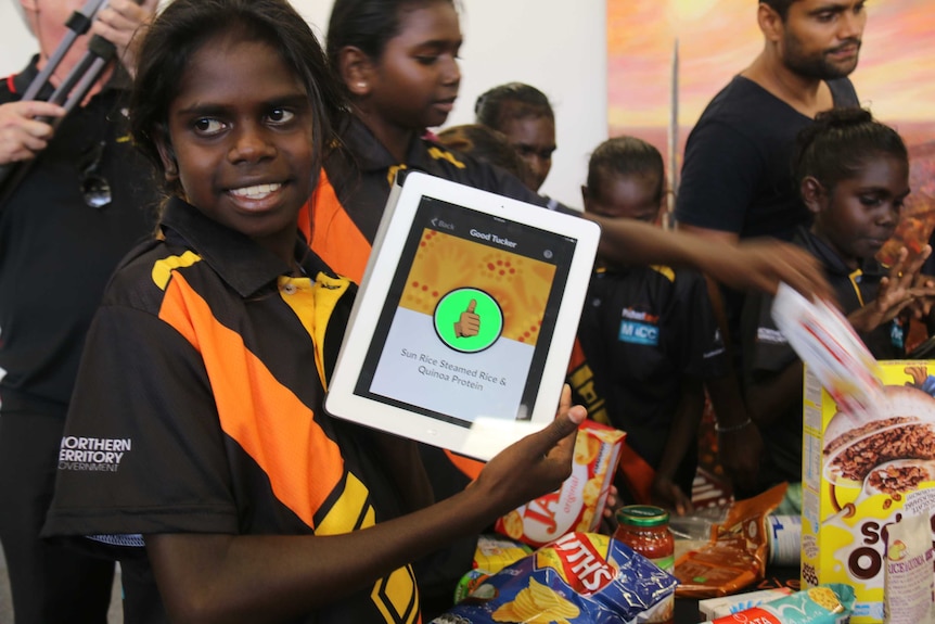 A girl holds up an app on an ipad showing a thumbs up.