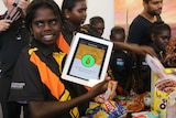 A girl holds up an app on an ipad showing a thumbs up.