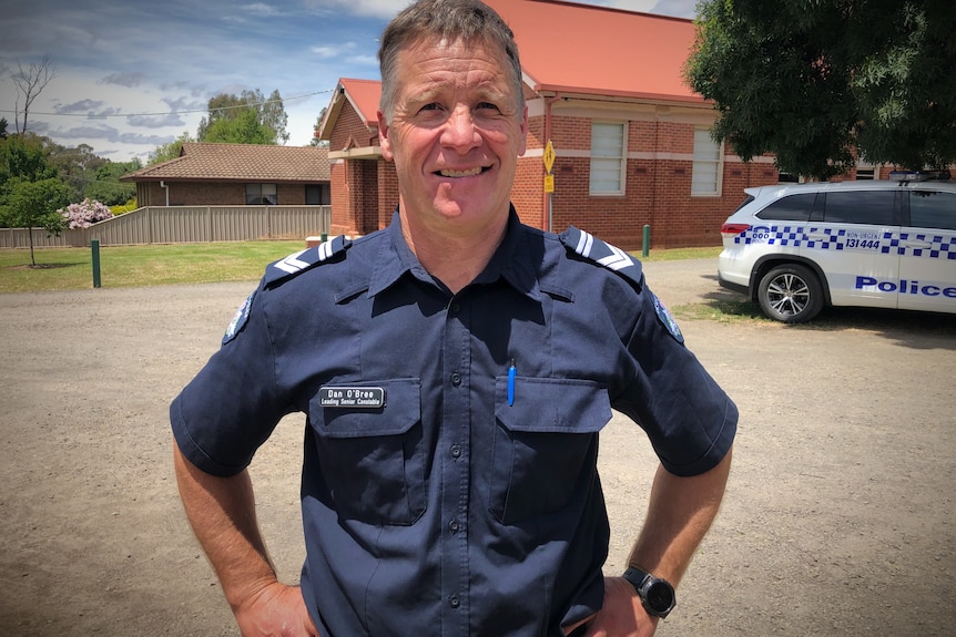 a police officer stands in his uniform with his hands on his hips.