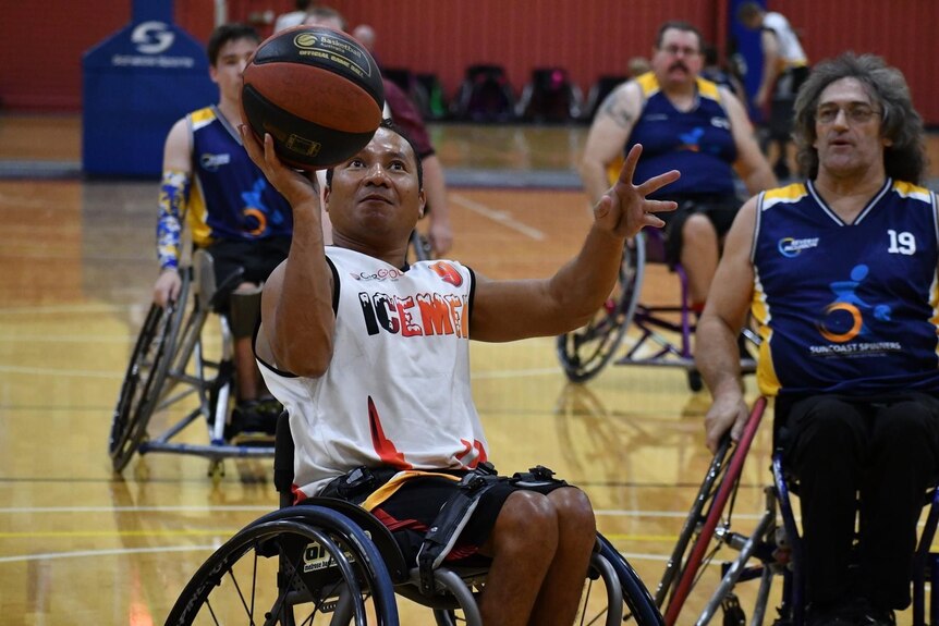 A man playing wheelchair basketball lines the ball up to shoot.