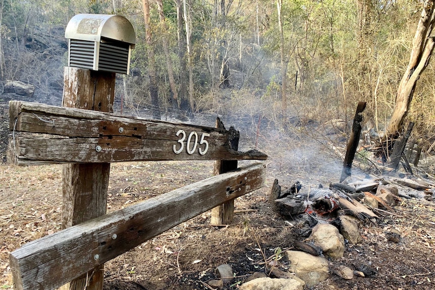 A burnt out letterbox and bushland.