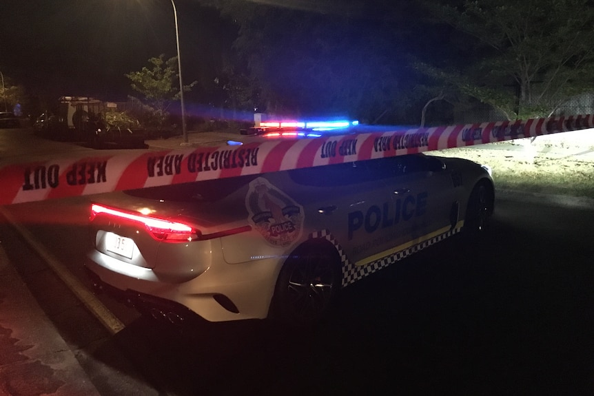 a police car on a suburban street behind police tape