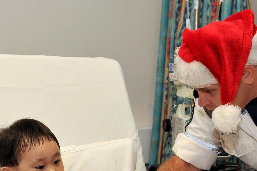 Police rescue officer Marcus Backway talks with patient Harry Ren, 3, during a Christmas Day visit