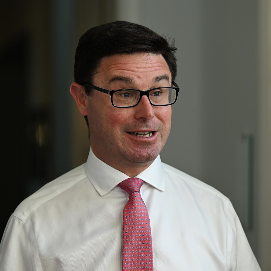 A man with a white shirt, glasses and pink tie