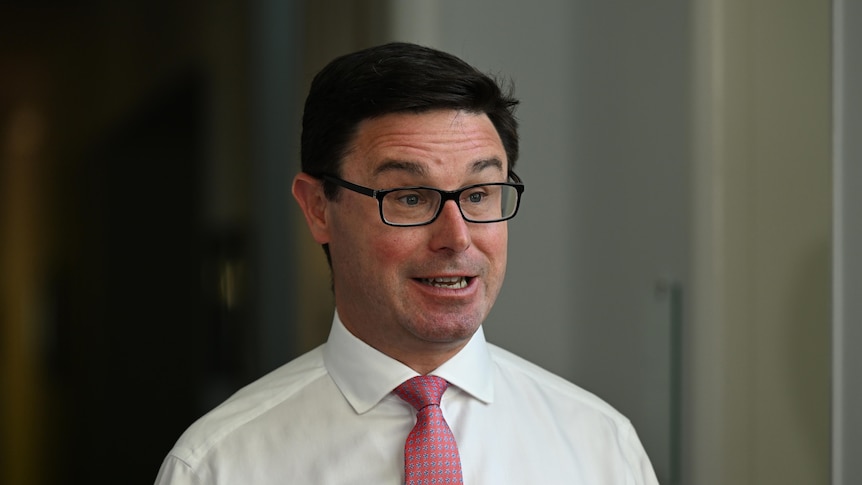 A man with a white shirt, glasses and pink tie