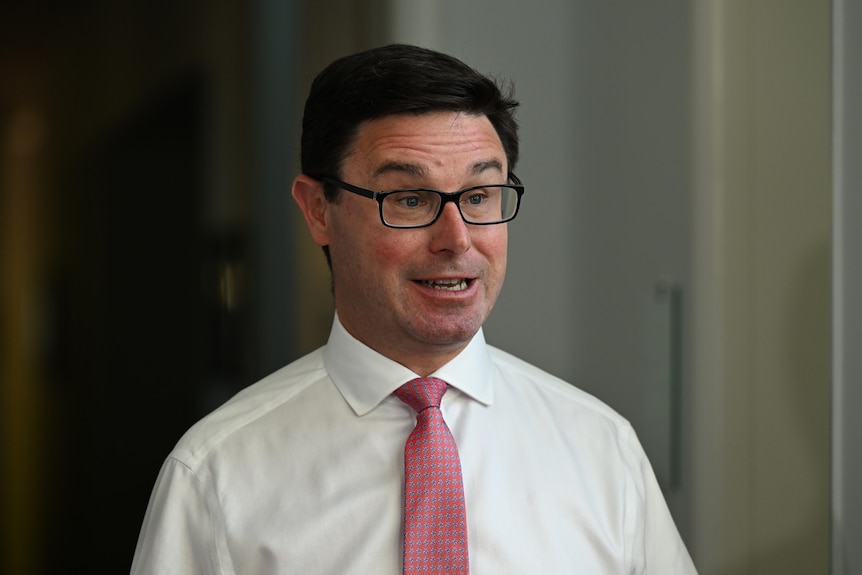 A man with a white shirt, glasses and pink tie