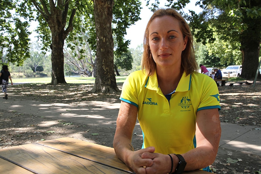 Eliza Ault-Connell sits at picnic table with trees in background