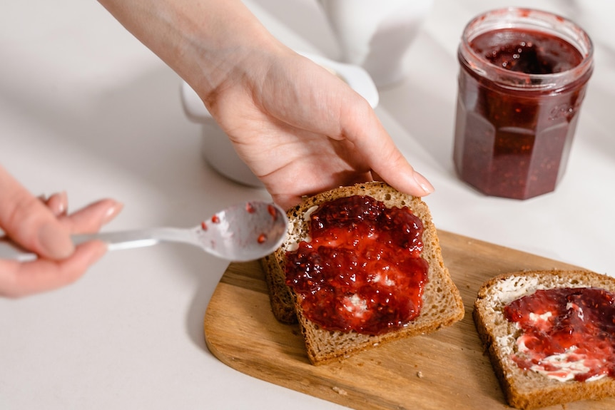 Woman spreading strawberry jam on toast