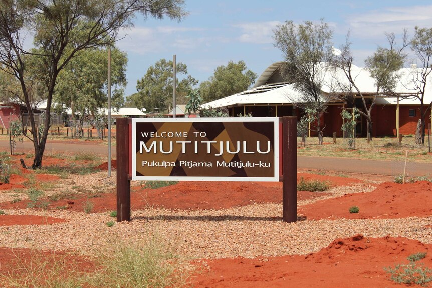 A sign outside a low building in the desert. It reads "Mutitjulu".