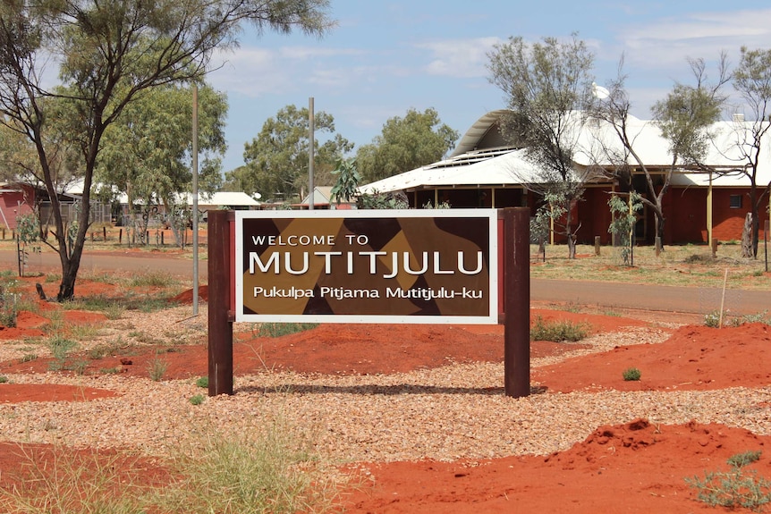 A sign outside a low building in the desert. It reads "Mutitjulu".