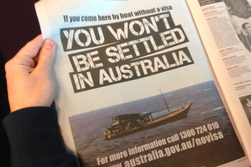 Person holding Government advertisement on asylum seeker deal