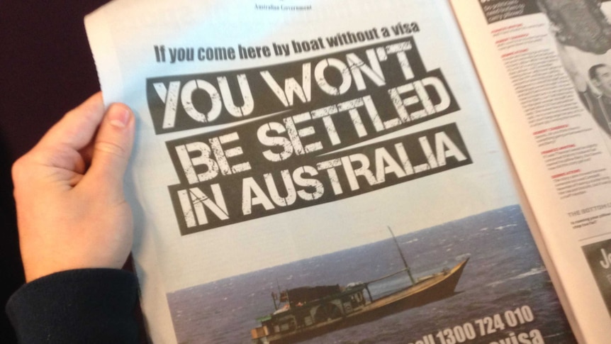 Person holding Government advertisement on asylum seeker deal