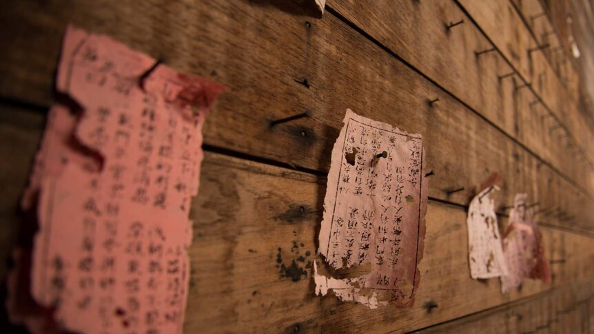 Tattered remains of prayer cards, recipes and messages hang on nails hammered into the wall of the meeting hall.