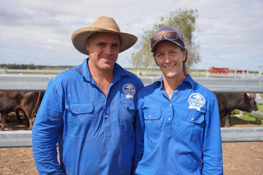 A man and a woman, wearing blue work shirts