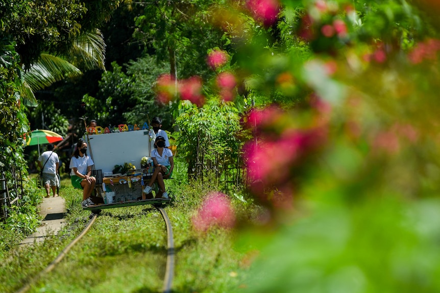 Student volunteers ride on their makeshift trolley through a green landscape