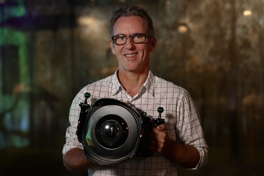 Gary holds a large camera.