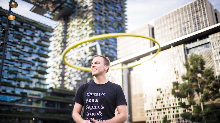 Dr Chris Ferrie stands smiling in a park near Central Station in Sydney CBD.